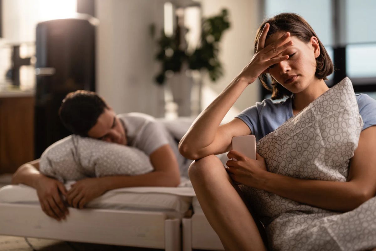Couple sitting apart looking emotionally disconnected and anxious