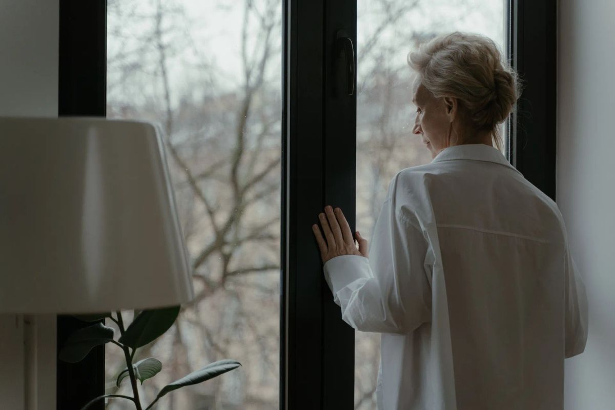 Person standing by window looking outside