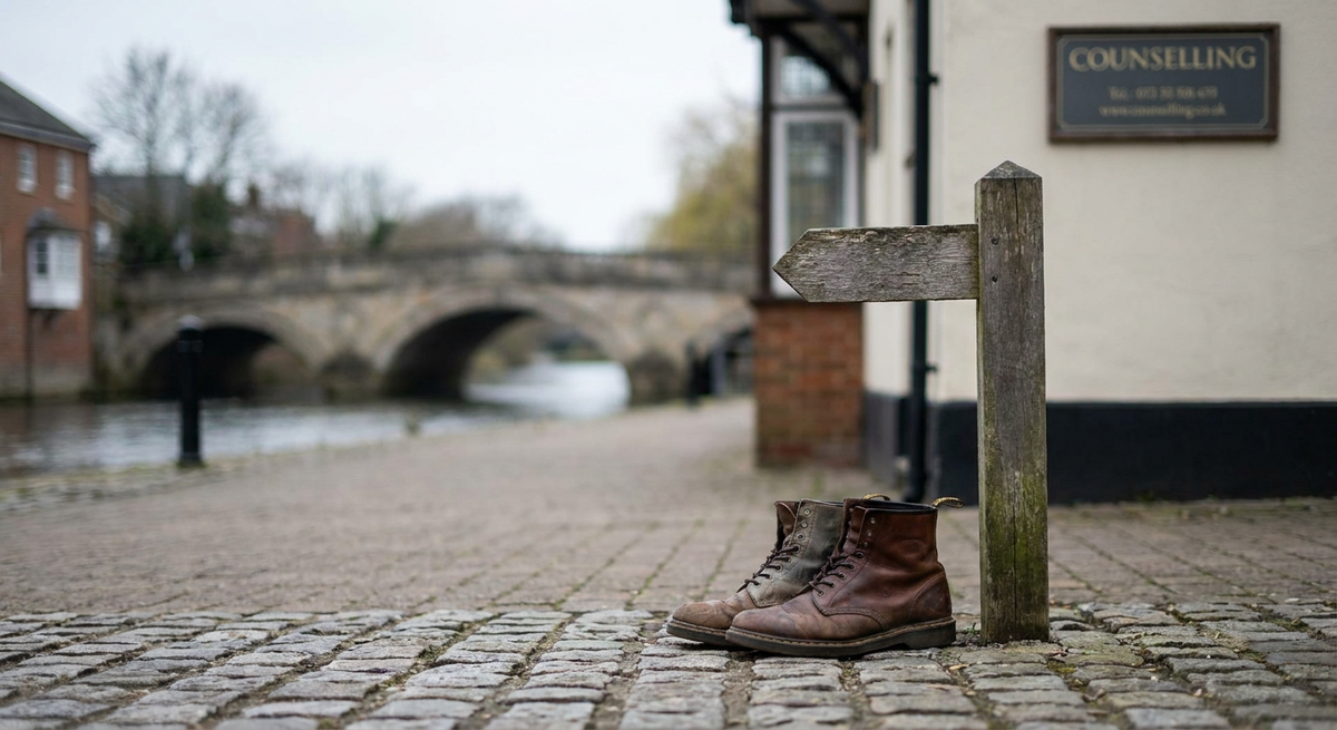 Brown leather boots beside a wooden signpost on a cobbled riverside path.