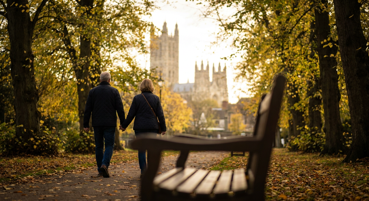 Couple walking hand in hand through an autumn park towards a historic cathedral.
